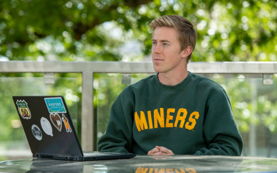 Photo of young man with laptop sitting outside