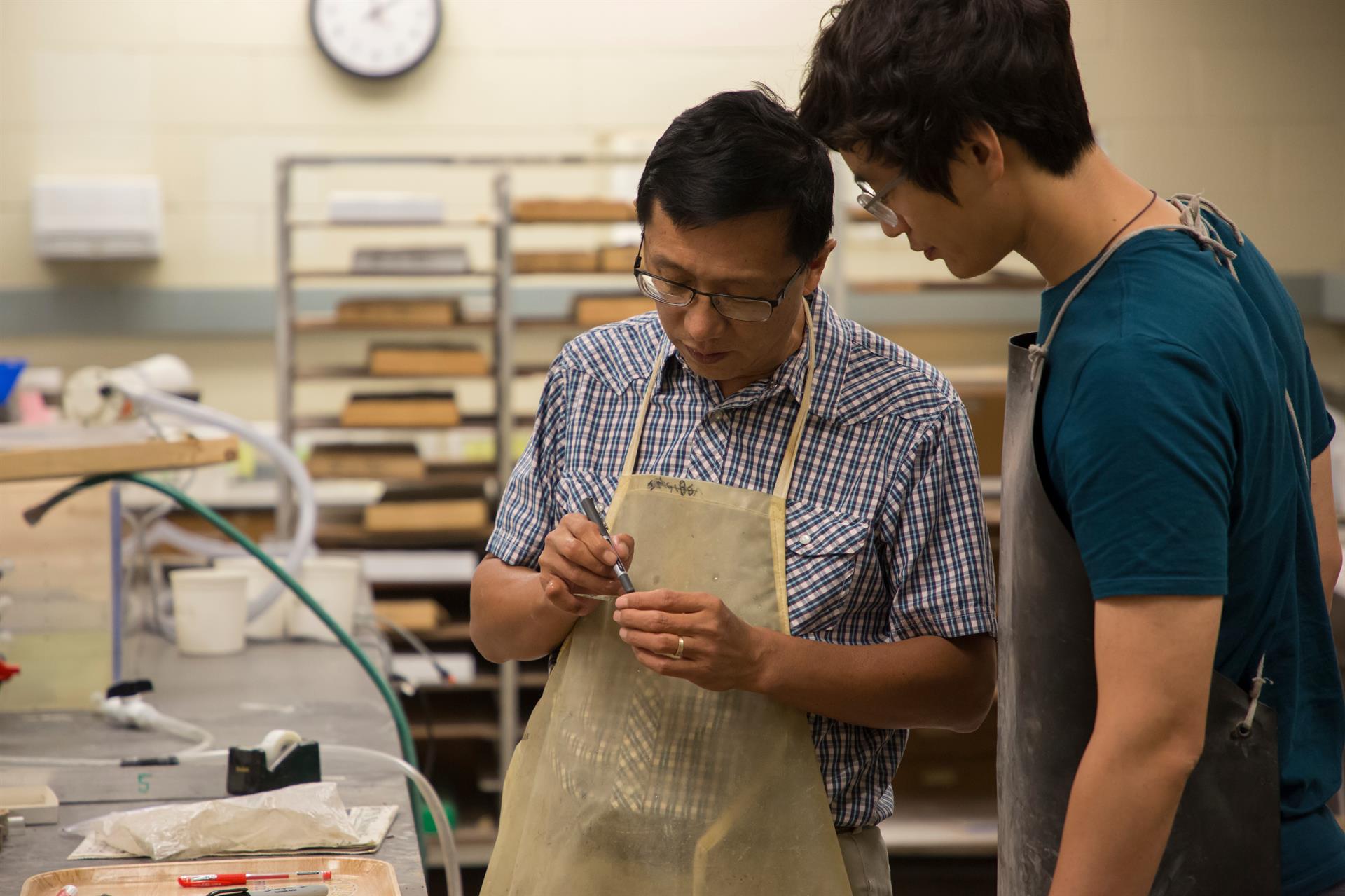 Dr. Wan Yang shows his research student Ziyue Ju how to properly label and cut rock samples for analysis.