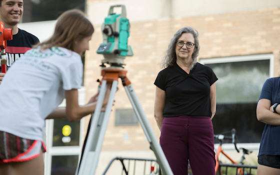 Image of Christi Luks observing a student's work with Engineers without Borders.