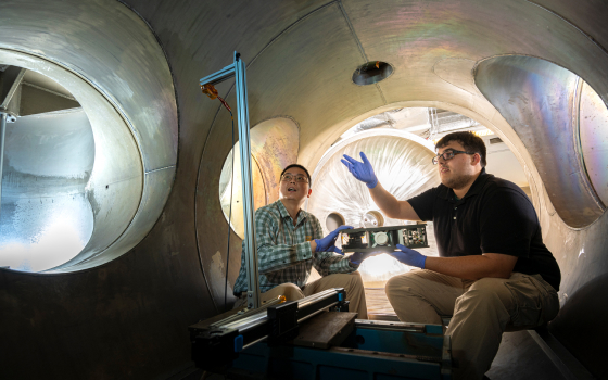 Dr. Daoru Han, left, and Jacob Ortega discuss engineering techniques inside a plasma vacuum chamber.