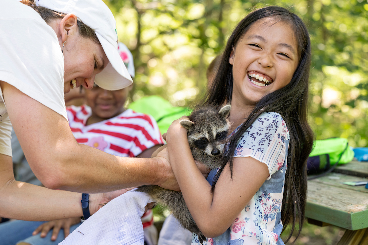 Camper holds a raccoon. 