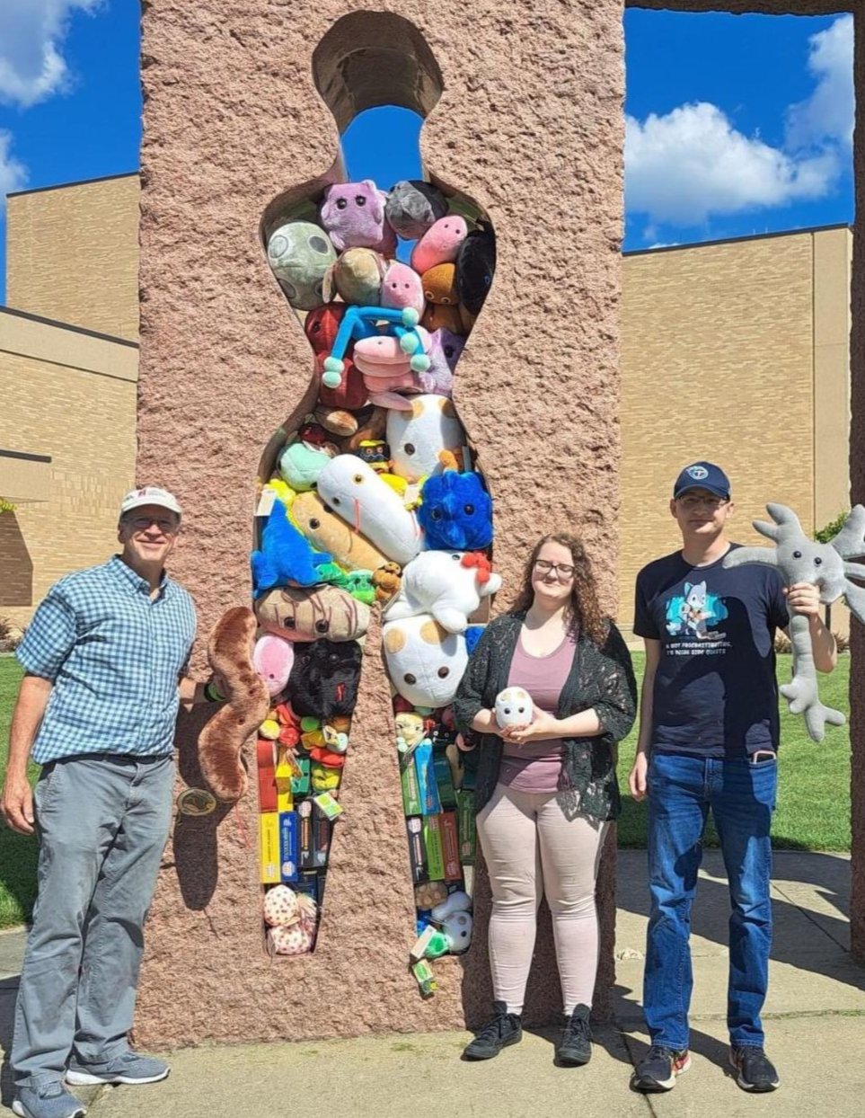 A Missouri S&T professor and two students stand in front of the Leach Theatre Millennium Arch, since they had filled the arch with microbe plushies.