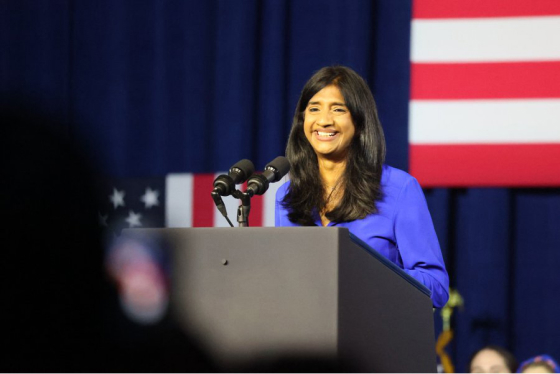 Aruna Miller stands at a podium smiling